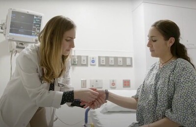 Врач держит пациентку за руку